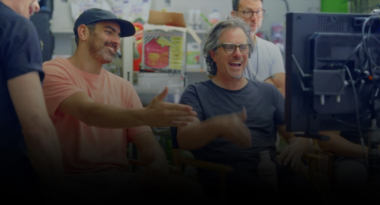 Imagem de dois cineastas sentados assistindo e gesticulando para a tela de projeção.